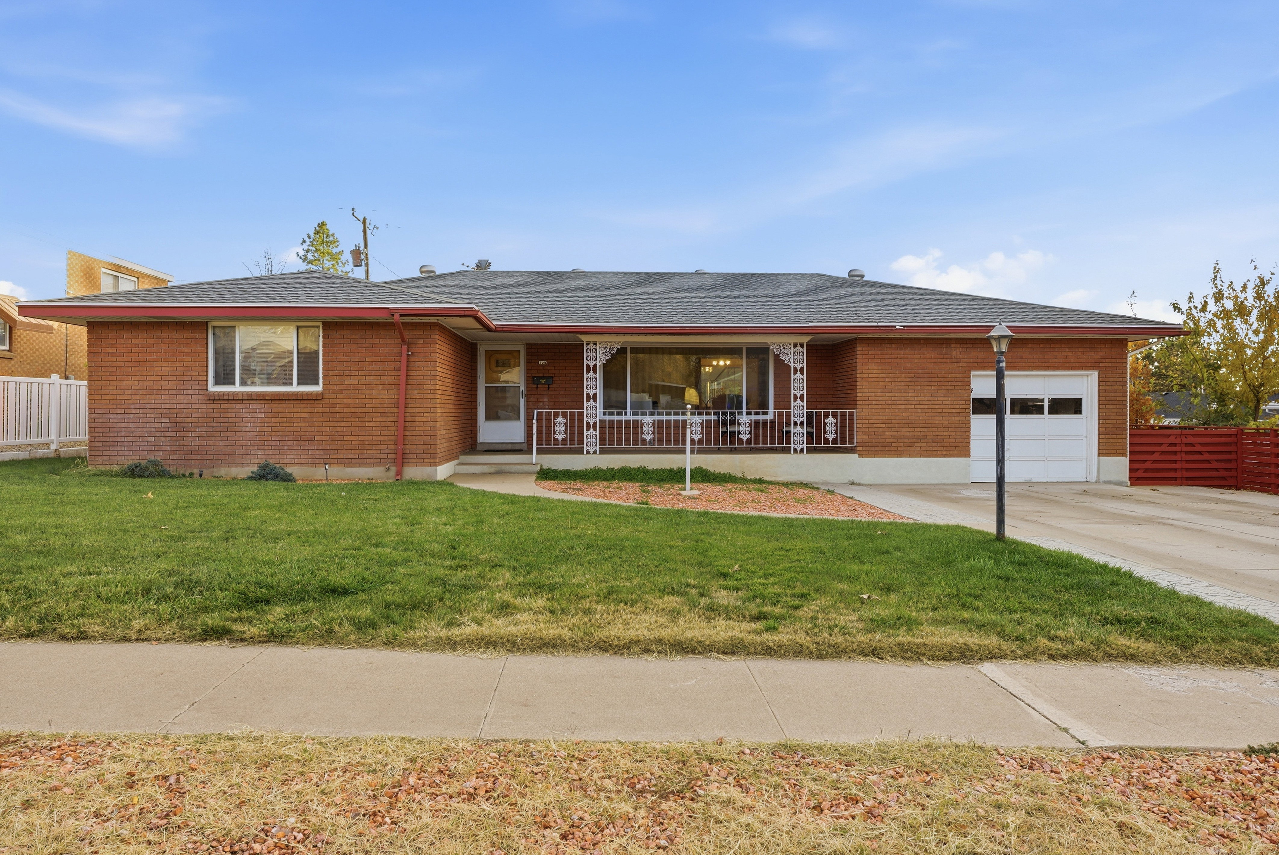 Ranch-style home featuring brick siding, roof with shingles, an attached garage, concrete driveway, and a porch