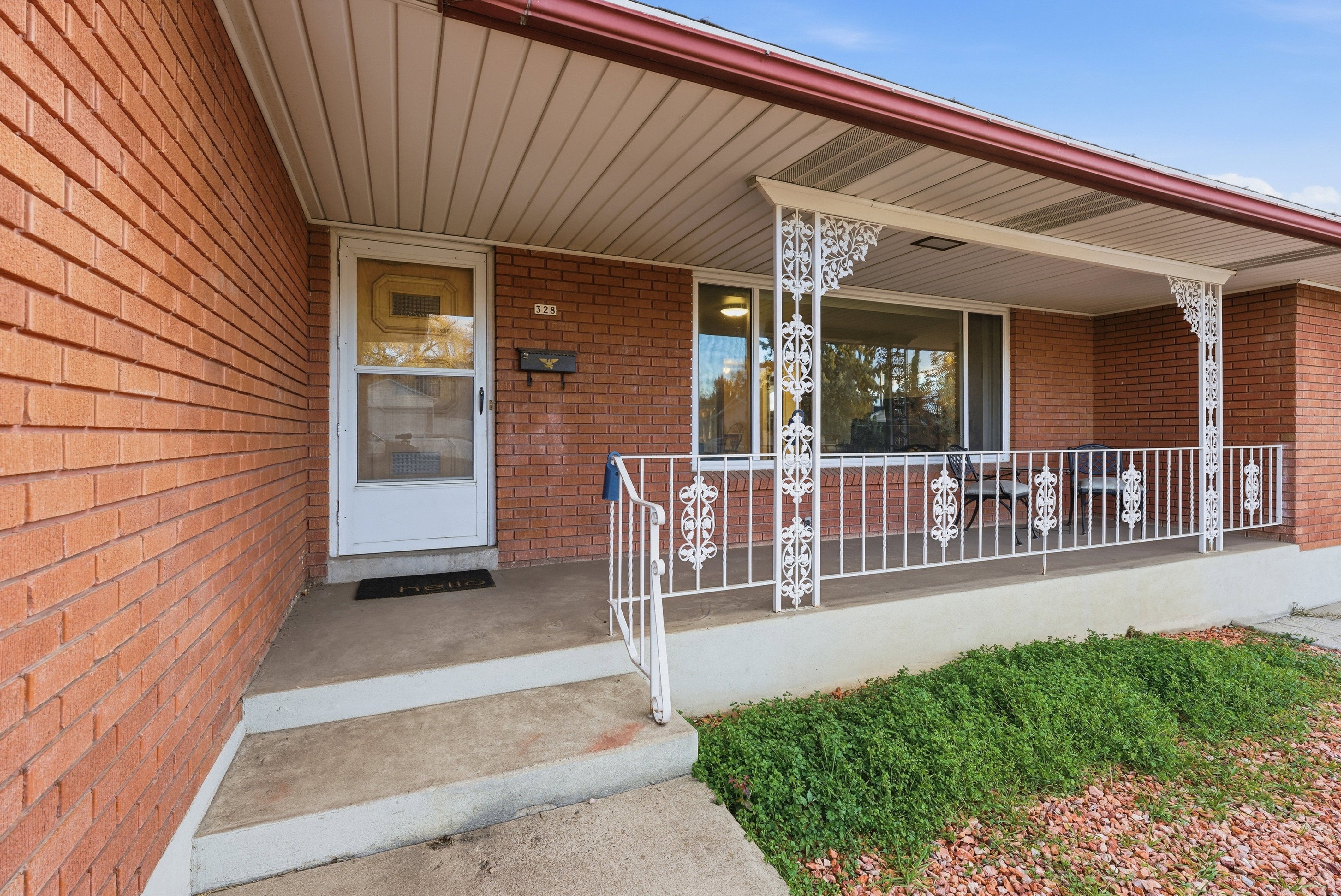 Doorway to property with covered porch and brick siding