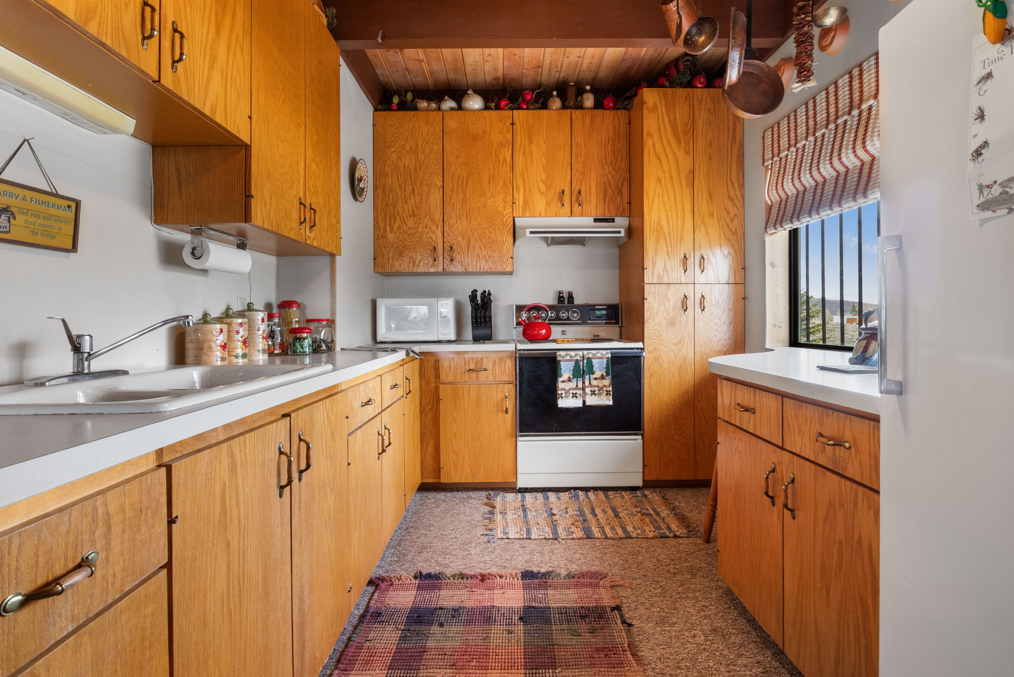 Kitchen featuring white appliances, light countertops, and wood finish cabinetry
