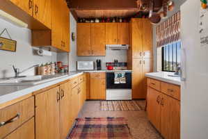 Kitchen featuring white appliances, light countertops, and wood finish cabinetry
