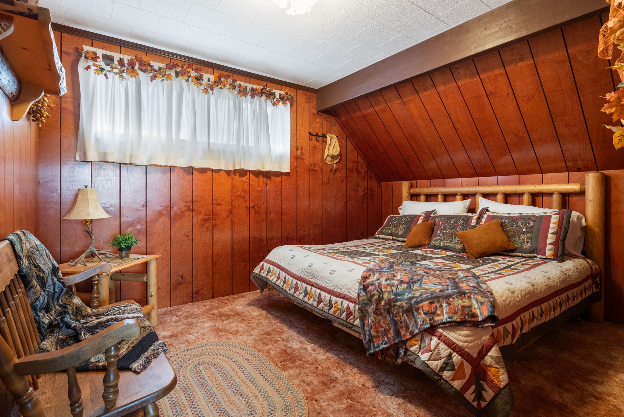 Carpeted bedroom with wood walls and vaulted ceiling