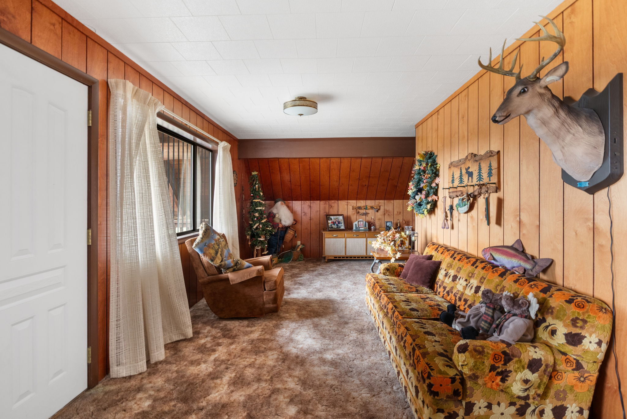 Living area with wood walls and dark colored carpet