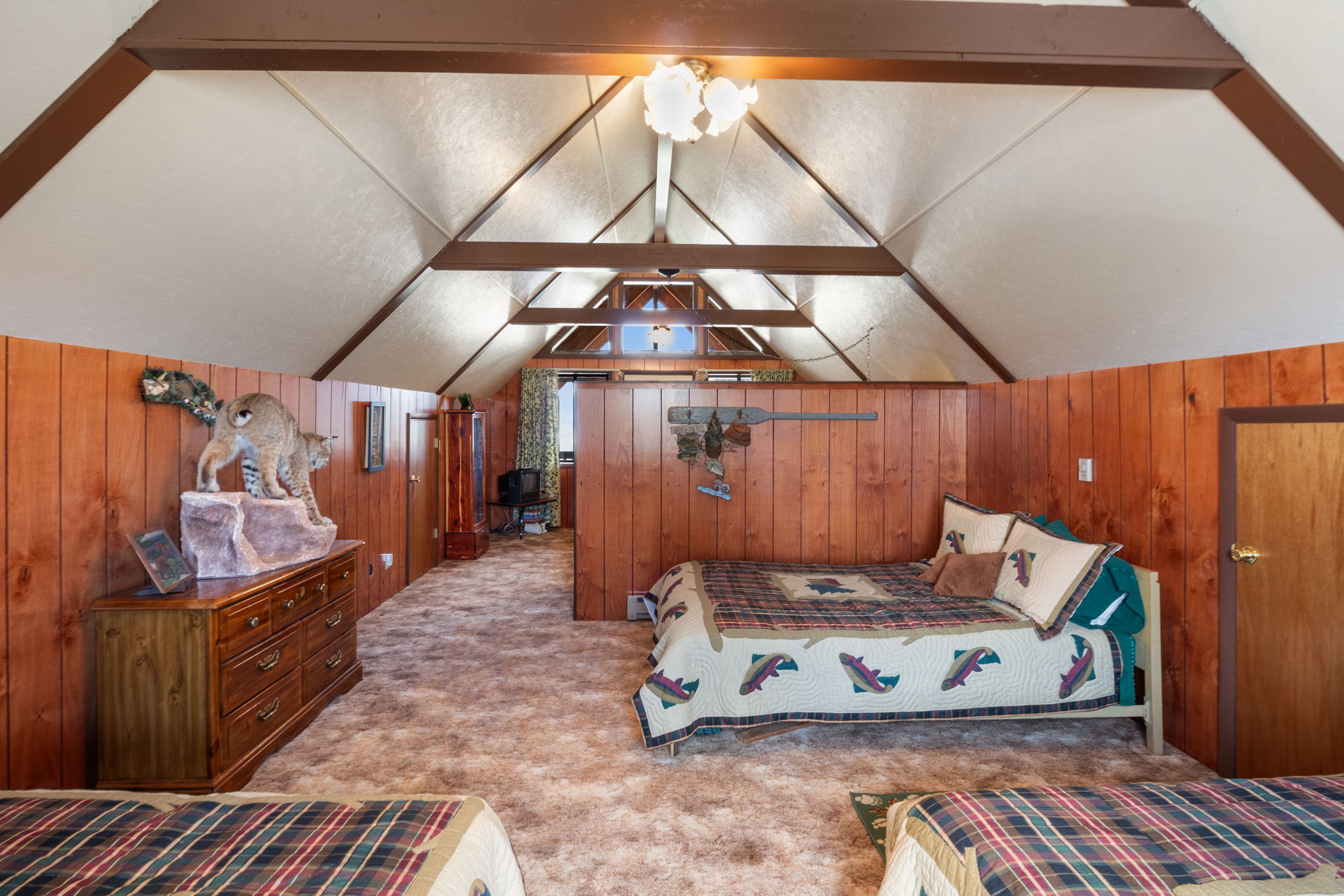 Carpeted bedroom with wood walls and suspended lighting