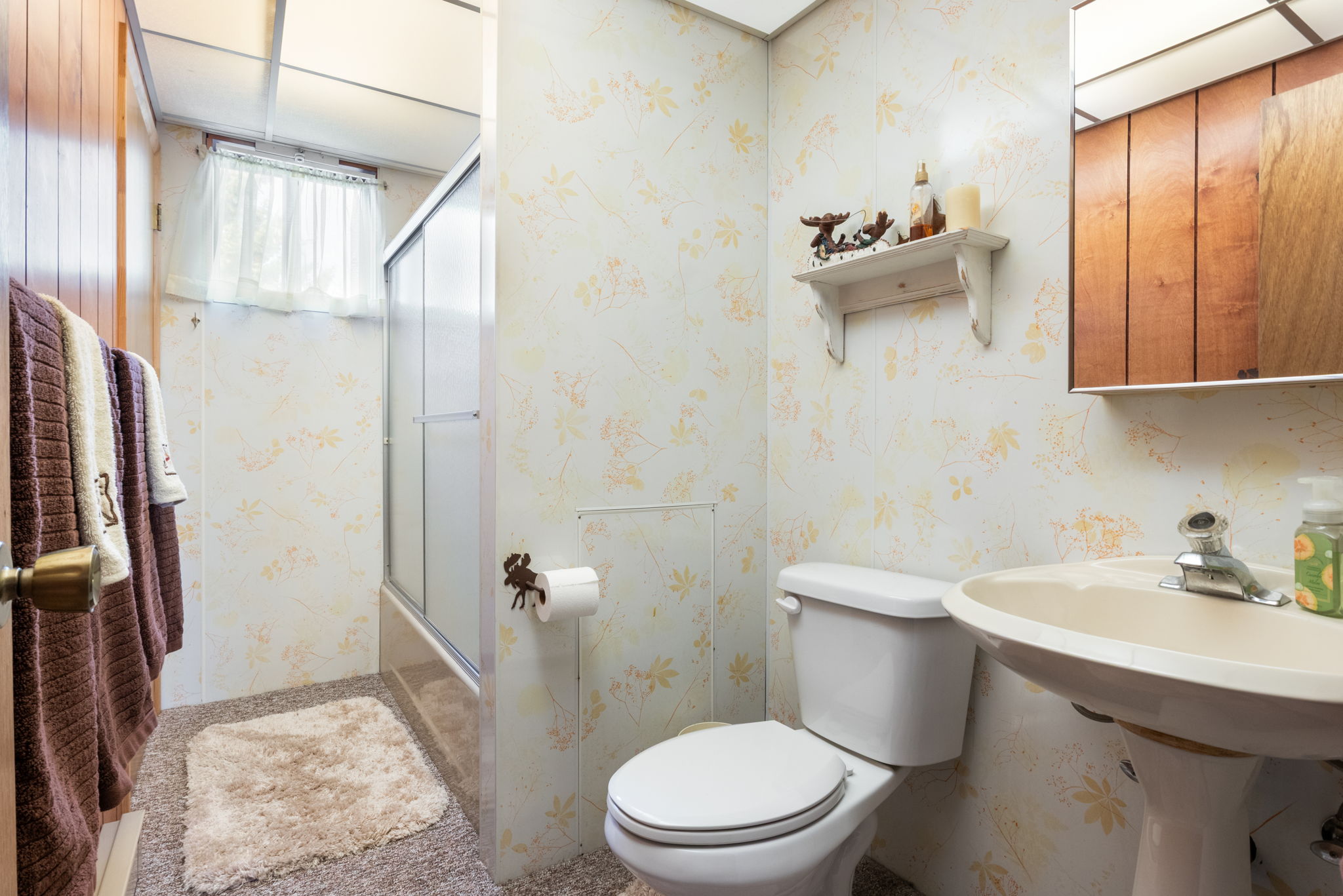 Bathroom featuring wallpapered walls and enclosed tub / shower combo