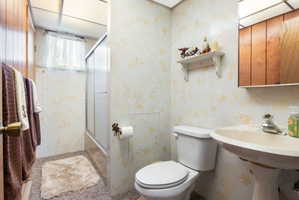 Bathroom featuring wallpapered walls and enclosed tub / shower combo
