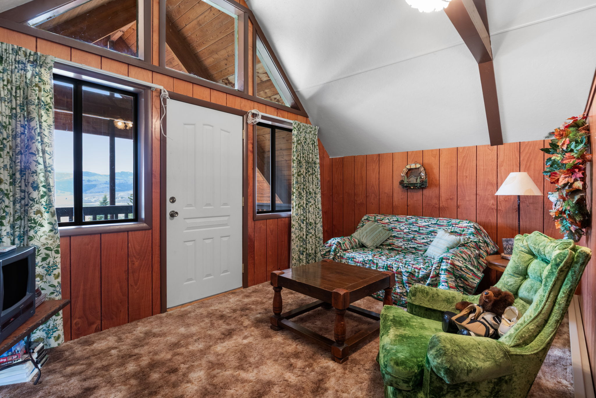 Living area with wood walls, beamed ceiling, and carpet flooring