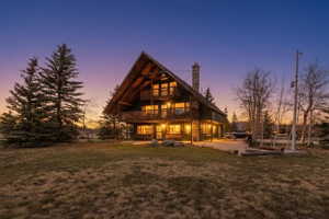 Back of property at dusk featuring a yard, a chimney, and a patio area