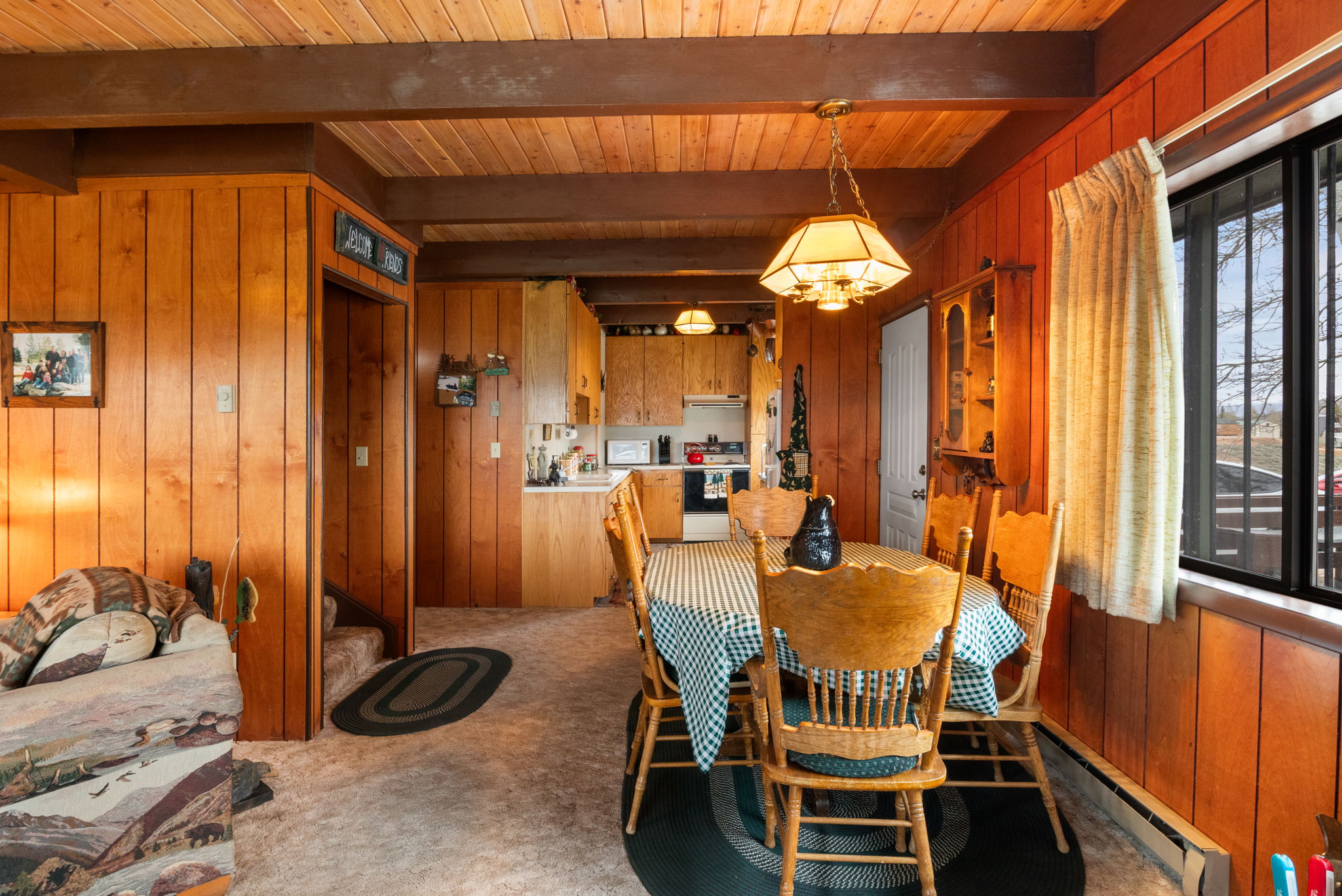 Dining space featuring wood walls, baseboard heating, beam ceiling, and carpet flooring