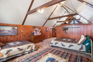 Carpeted bedroom featuring wooden walls and beam ceiling