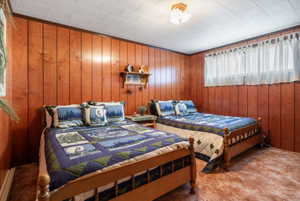 Bedroom with wooden walls, carpet flooring, and a baseboard heating unit