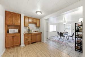 Kitchen with light countertops, ceiling fan, white microwave, wood finish cabinetry, and wood finish floors