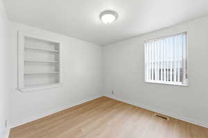 3rd bedroom featuring built in shelves and light wood LVP flooring