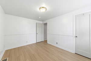 2nd bedroom featuring light wood LVP flooring and wainscoting
