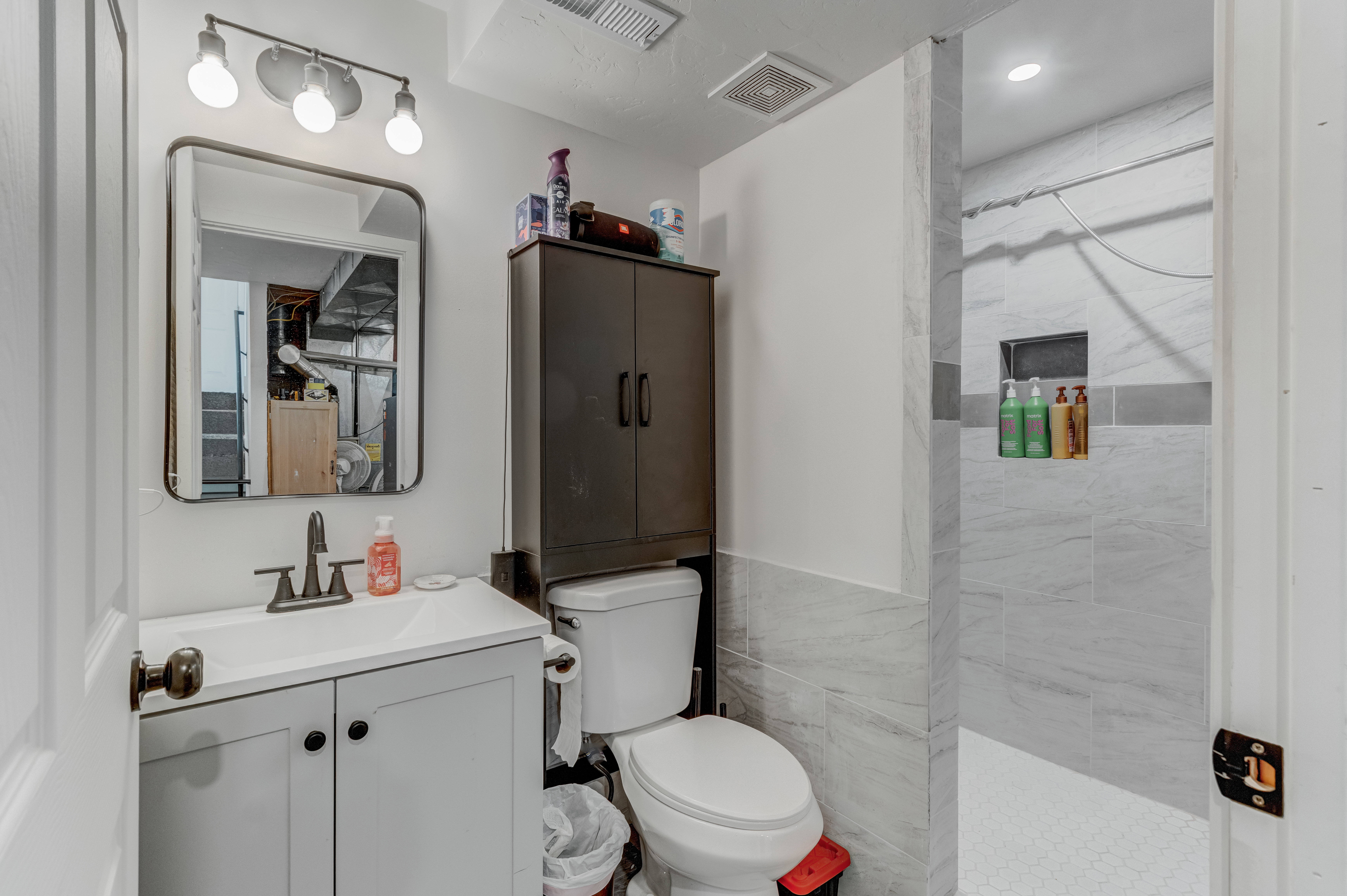 Bathroom featuring a walk in shower, vanity, and tile walls