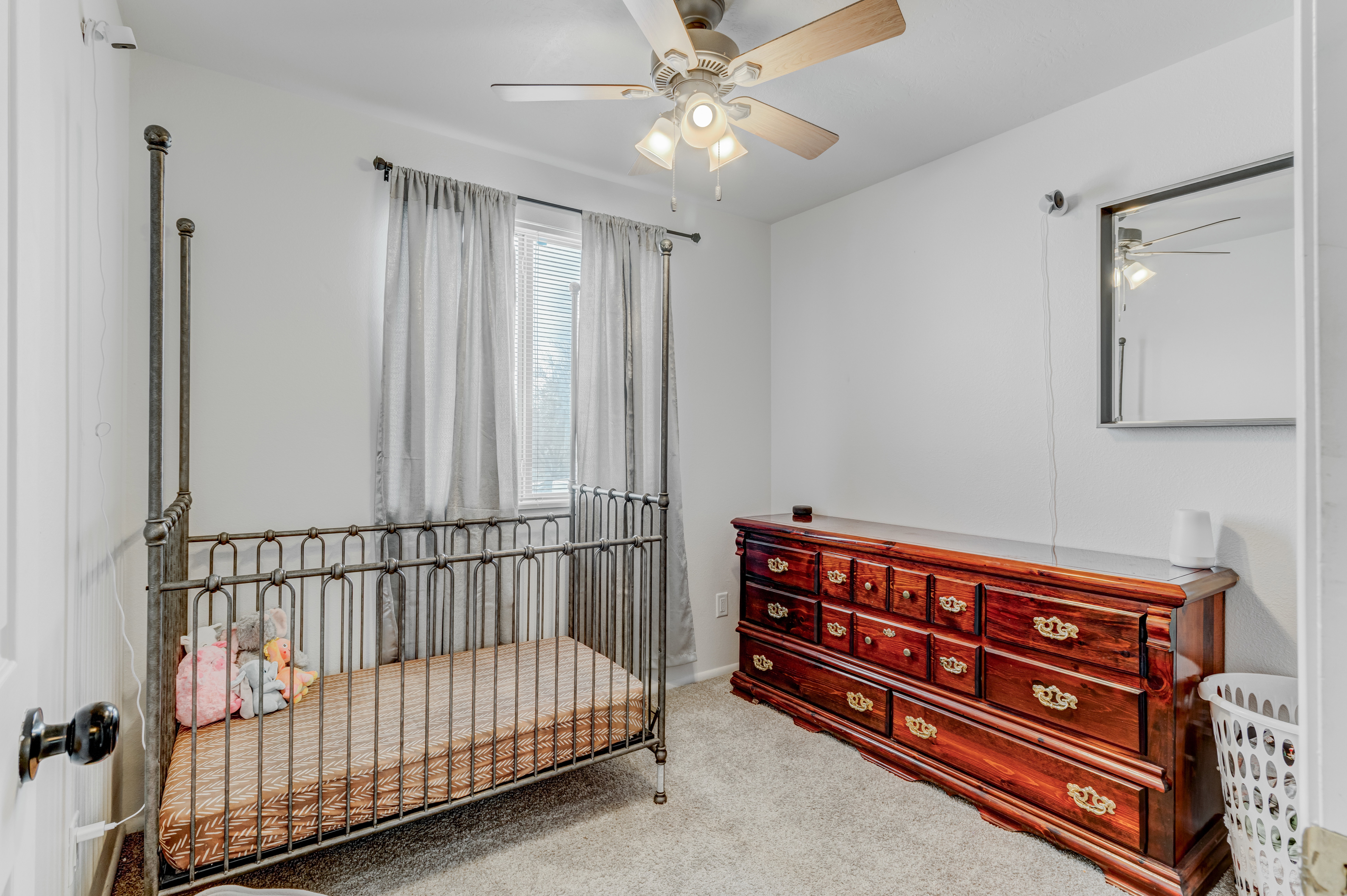 Bedroom featuring a crib, light carpet, and ceiling fan