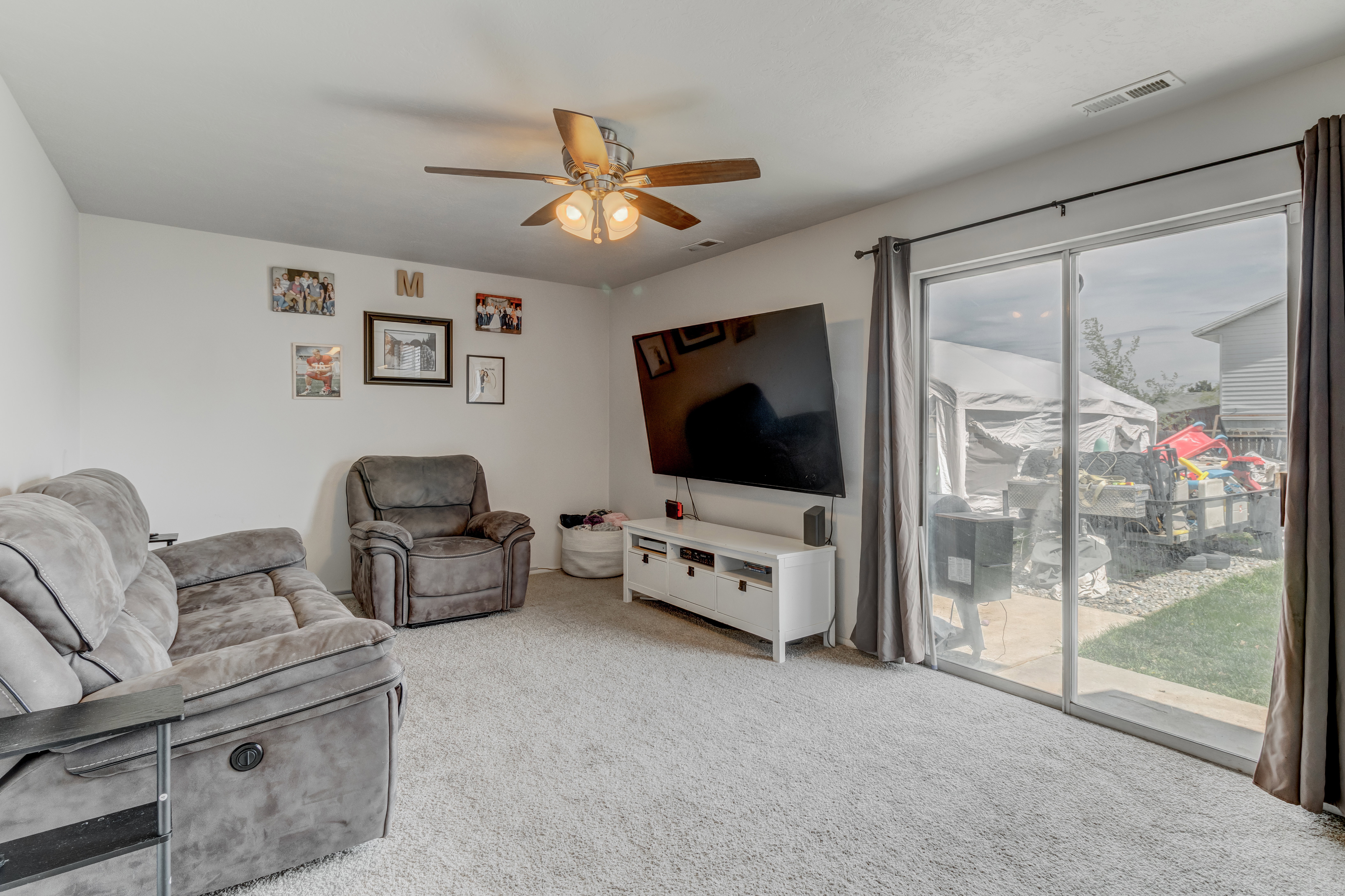 Living area featuring light colored carpet and ceiling fan