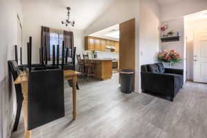 Living room featuring lofted ceiling, light wood-style flooring, and suspended lighting