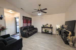 Living area featuring light wood finished floors, vaulted ceiling, and ceiling fan