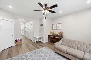 Living area featuring light wood-style floors, ceiling fan, and recessed lighting