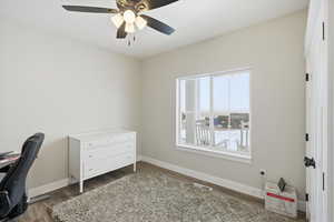 Office area with dark wood-style flooring and ceiling fan