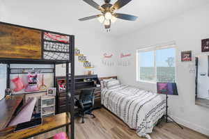 Bedroom featuring a desk, light wood-style flooring, and ceiling fan