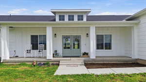 Entrance to property with roof with shingles, a porch, and board and batten siding