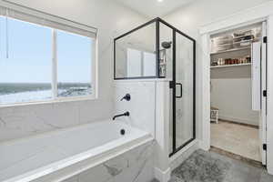 Bathroom featuring a marble finish shower, a spacious closet, and a garden tub
