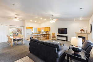 Living area featuring ceiling fan, vaulted ceiling, a tiled fireplace, and recessed lighting