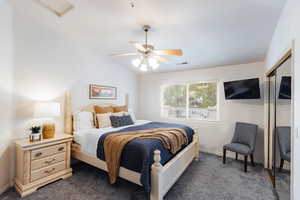 Bedroom with a closet, dark carpet, a ceiling fan, and lofted ceiling