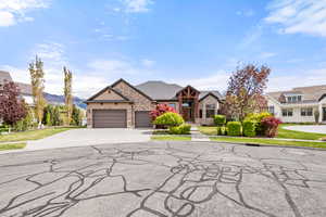 View of front of house featuring an attached garage, driveway, and stone siding