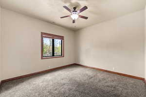 Carpeted spare room with a ceiling fan and baseboards