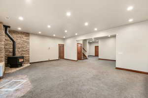 Below grade area featuring light colored carpet, a wood stove, and recessed lighting