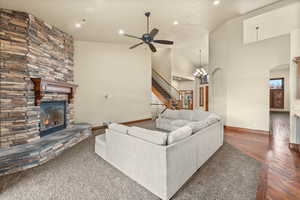 Living room with a fireplace, a chandelier, ceiling fan, hardwood / wood-style flooring, and vaulted ceiling