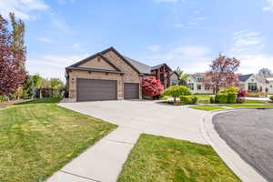Craftsman-style home featuring a front lawn, an attached garage, concrete driveway, stucco siding, and stone siding