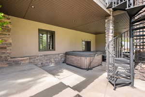 View of patio / terrace featuring stairway and a hot tub