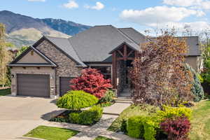View of front of house featuring stone siding, a garage, driveway, and stucco siding