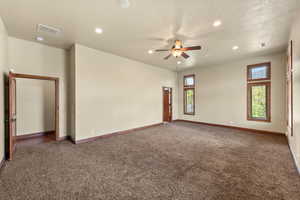Spare room with ceiling fan, dark carpet, and recessed lighting