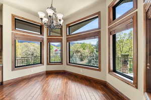 Unfurnished dining area with dark wood finished floors and a chandelier