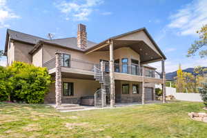 Rear view of house with a patio, stucco siding, a chimney, and stone siding