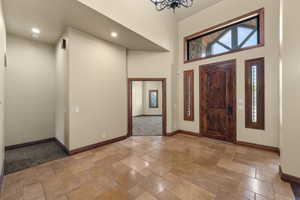 Entrance foyer featuring stone tile floors, a high ceiling, and suspended lighting