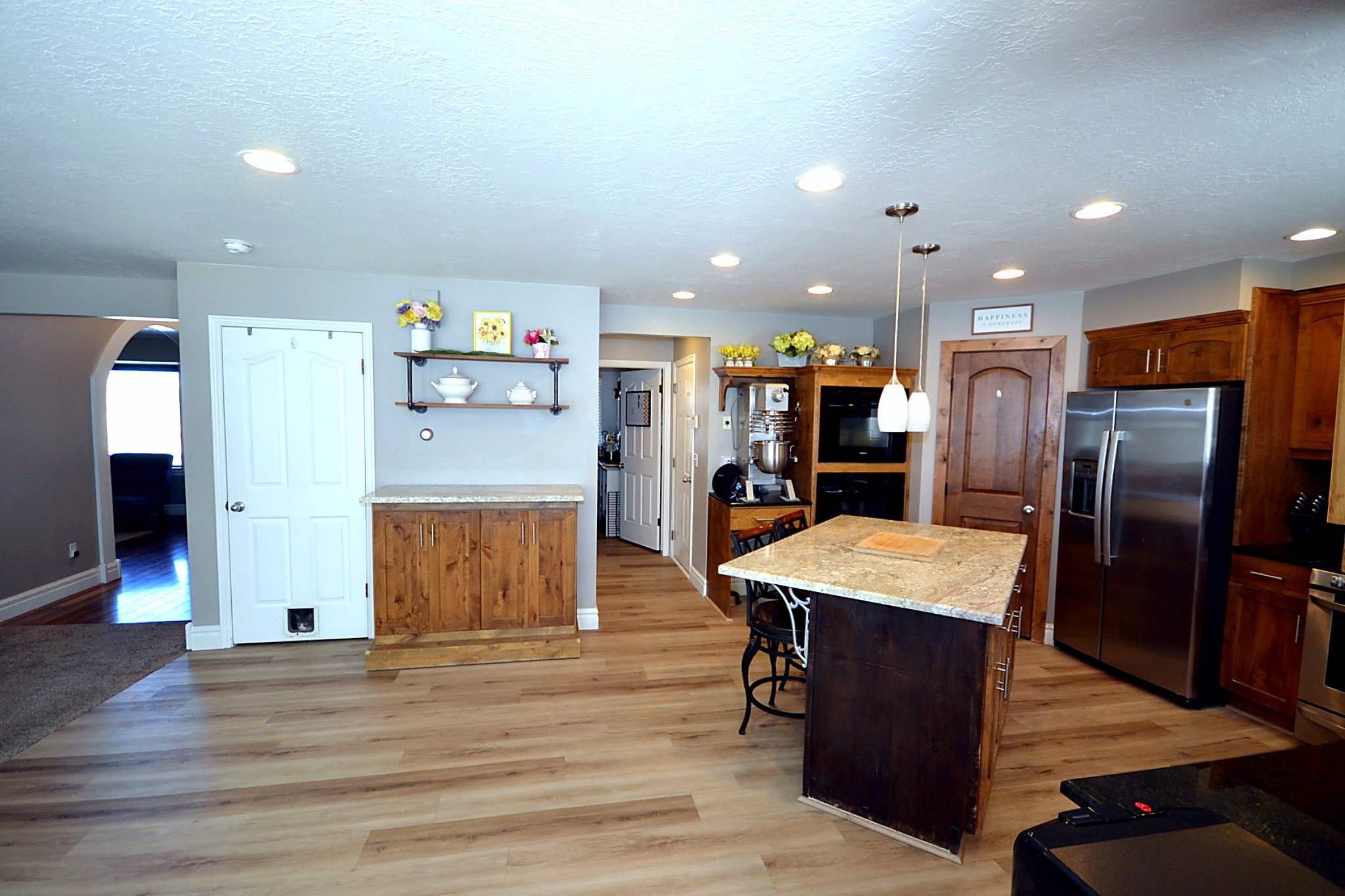 Kitchen with stainless steel appliances, light wood-type flooring, light stone countertops, a center island, and a kitchen breakfast bar