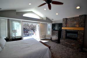 Bedroom featuring dark carpet, access to outside, recessed lighting, ceiling fan, and a fireplace
