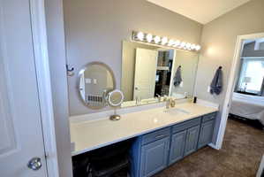 Ensuite bathroom with vanity, dark colored carpet, and vaulted ceiling