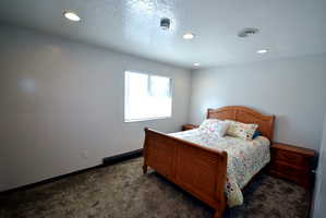 Bedroom featuring a textured ceiling, dark carpet, and recessed lighting