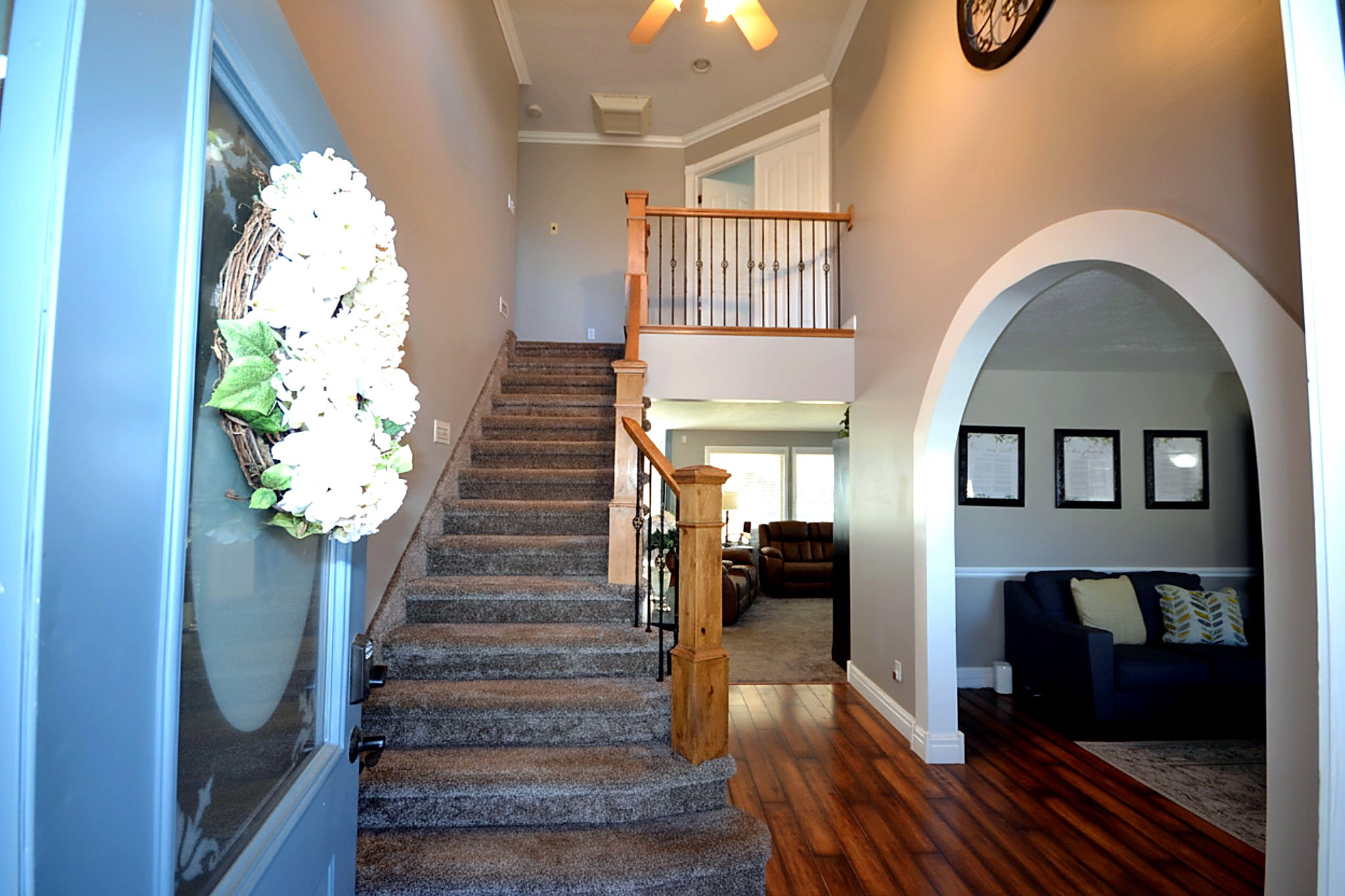 Stairway featuring a high ceiling, hardwood / wood-style floors, crown molding, and arched walkways