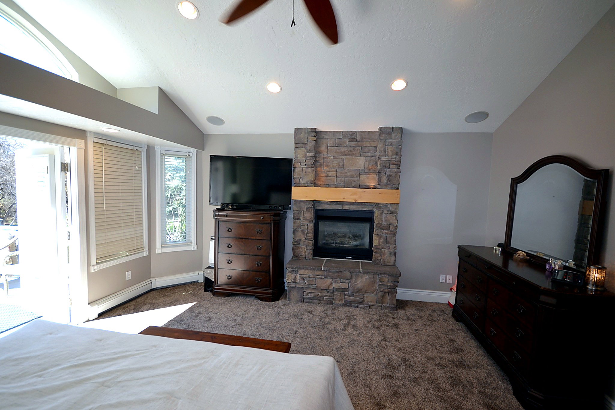 Bedroom with lofted ceiling, a ceiling fan, dark carpet, access to exterior, and a fireplace