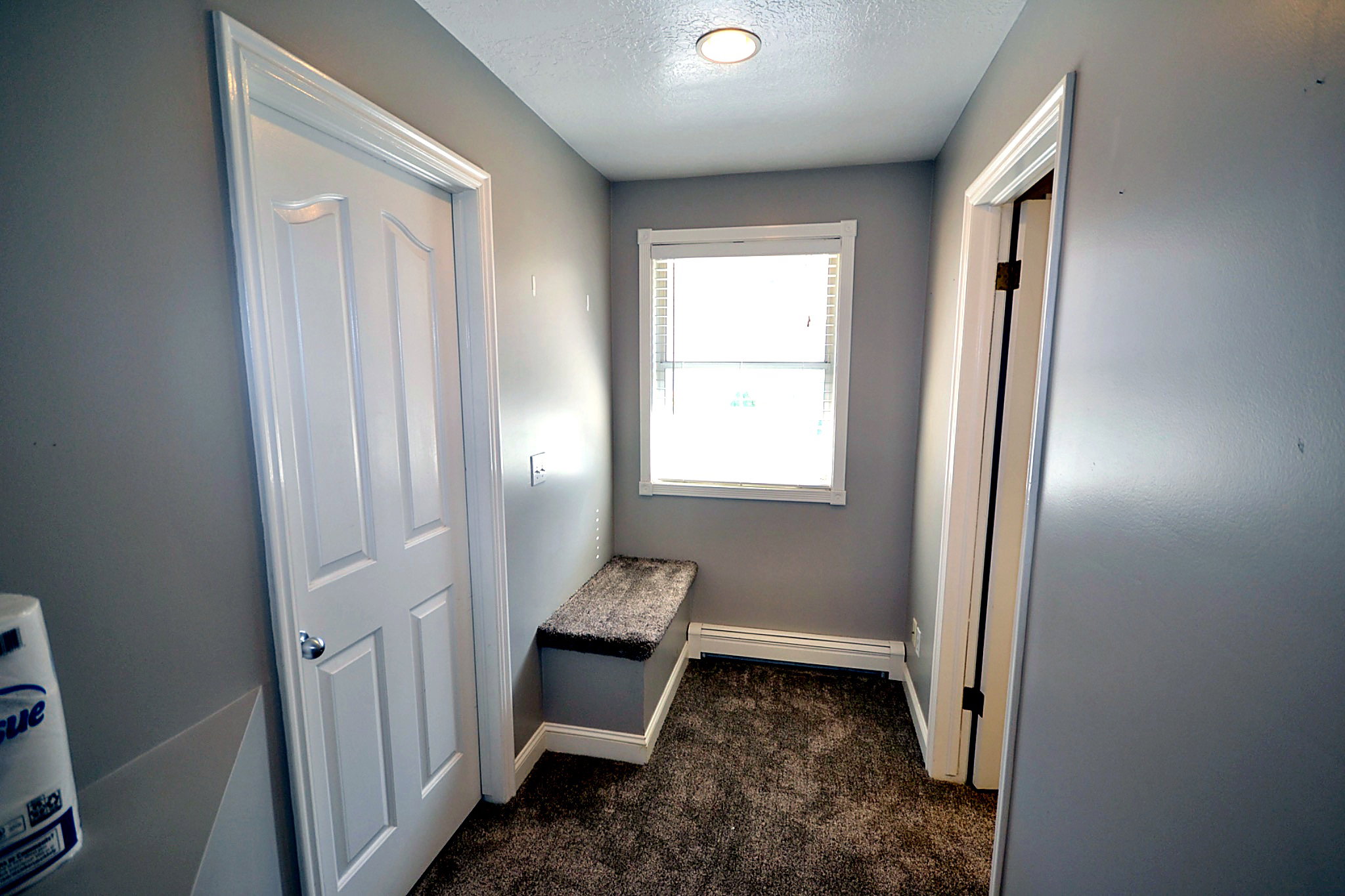 Hallway with dark carpet, a textured ceiling, and a baseboard heating unit
