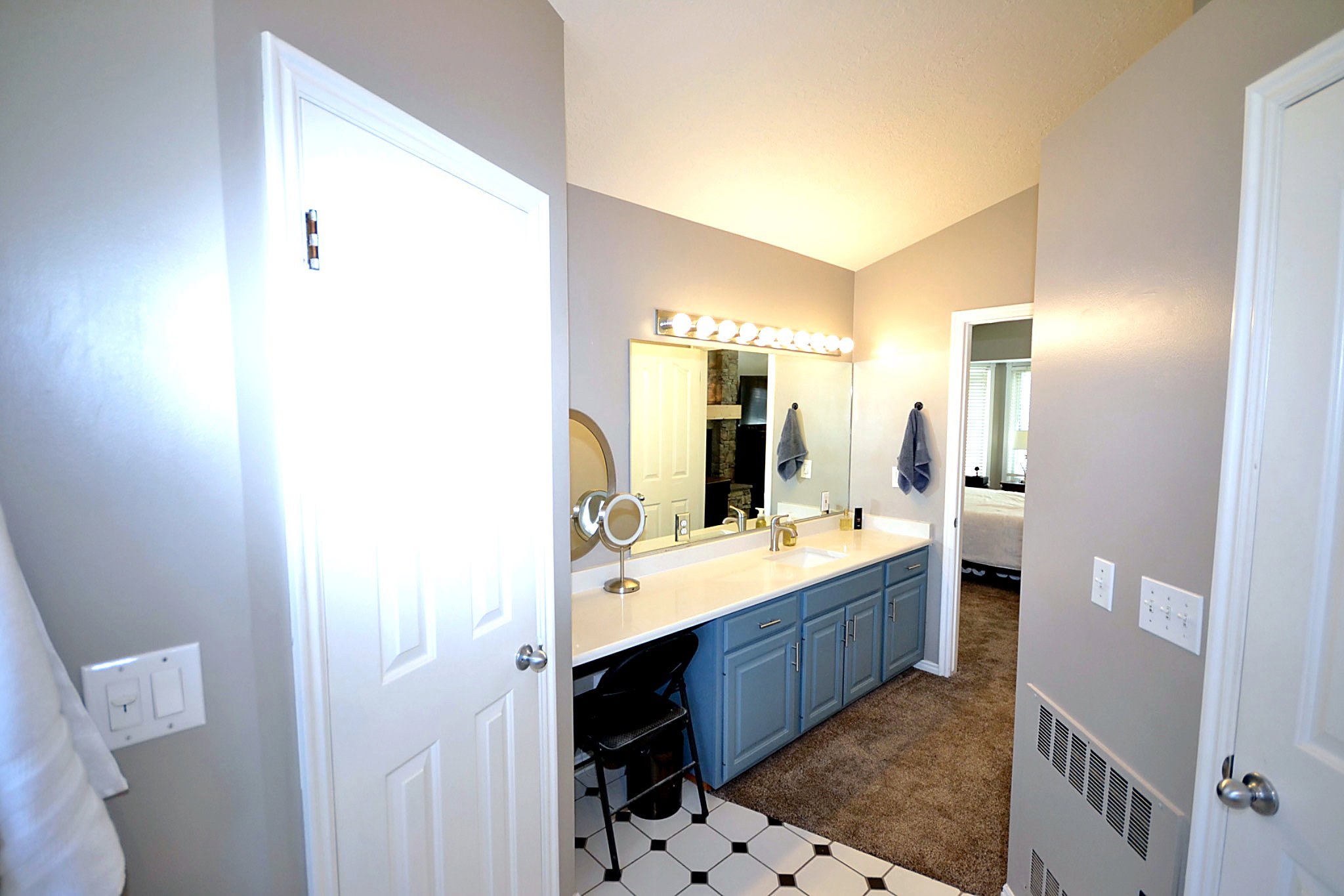 Bathroom featuring vanity, vaulted ceiling, ensuite bath, radiator heating unit, and dark carpet