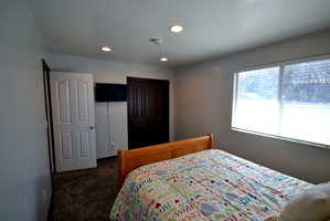 Bedroom featuring dark carpet, a textured ceiling, recessed lighting, and a closet