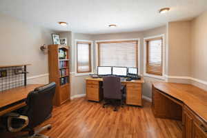 Office space with light wood-style flooring, a textured ceiling, and built in study area
